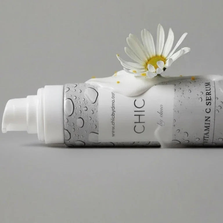 Skincare serum bottle with a daisy on a gray background