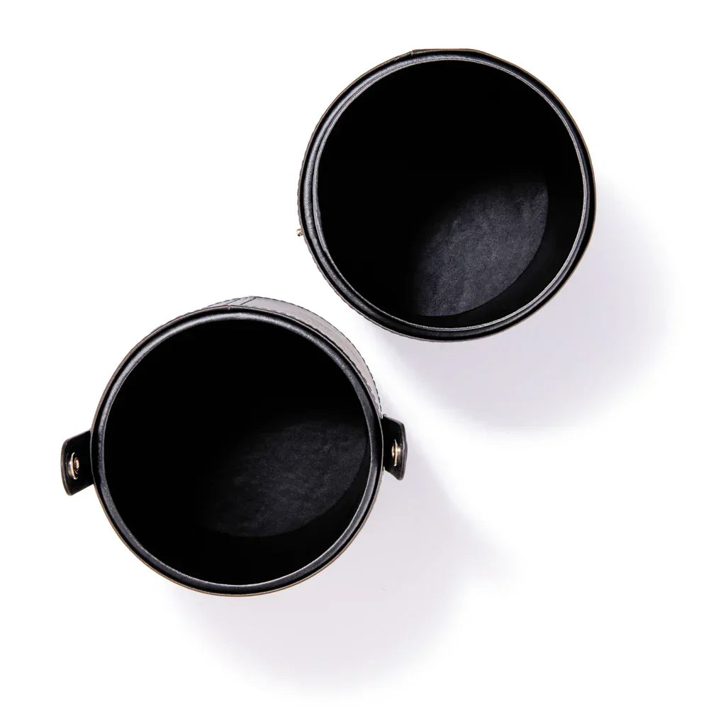 Black leather cosmetic jars with gold hardware, empty and open for beauty products