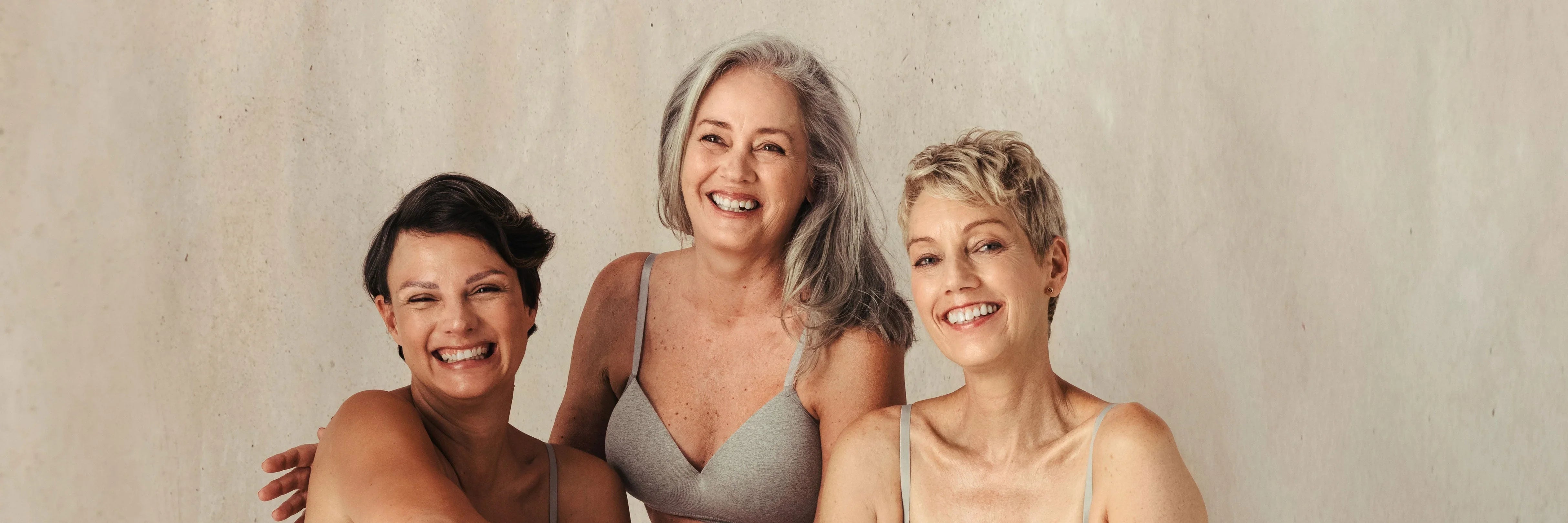 Three mature women smiling, showcasing natural beauty and healthy skin